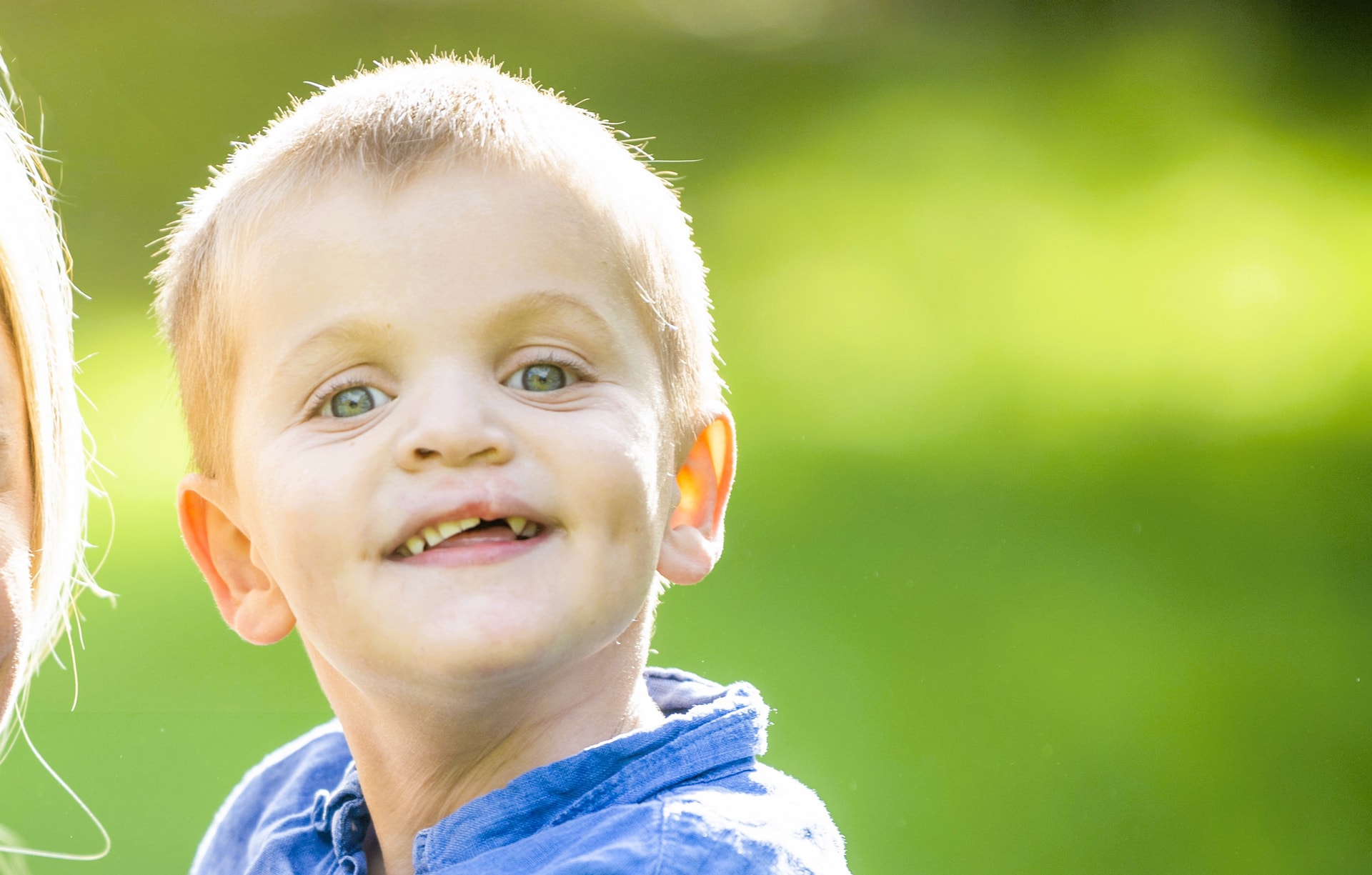 Junge mit Lippen-Kiefer-Gaumen-Segel-Fehlbildung (LKGSF) Fröhlicher Junge im Garten mit Lippen-Kiefer-Gaumen-Segel-Fehlbildung (LKGSF)